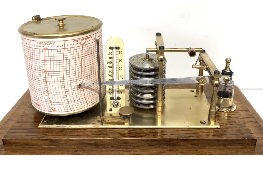 An antique oak cased barograph featuring a brass recording mechanism, internal thermometer, and bevelled glass cover over a base chart drawer. View IX