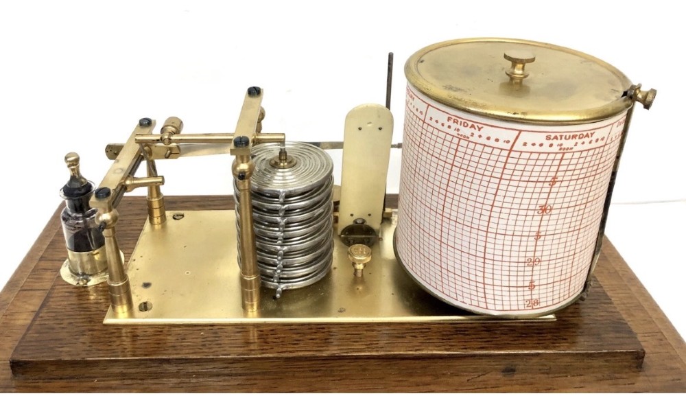 An antique oak cased barograph featuring a brass recording mechanism, internal thermometer, and bevelled glass cover over a base chart drawer. View XI