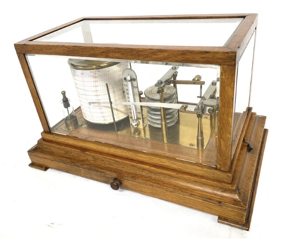 An antique barograph featuring brass recording mechanisms and a paper chart drum enclosed in a glazed oak case with a bottom chart drawer. View IV