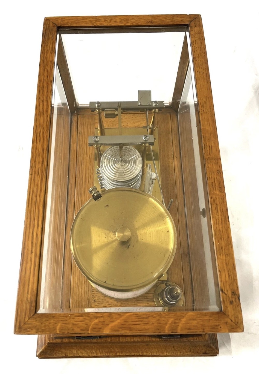 An antique barograph featuring brass recording mechanisms and a paper chart drum enclosed in a glazed oak case with a bottom chart drawer. View X