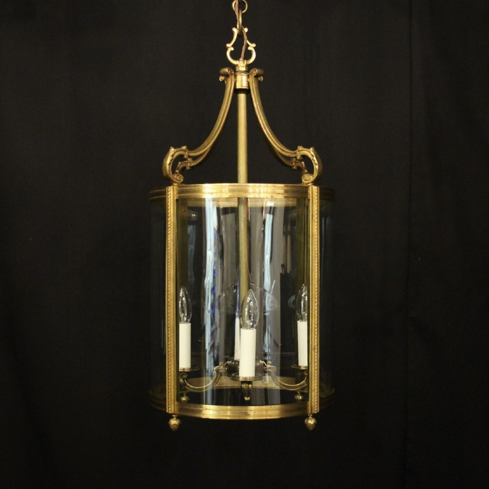 A French gilt bronze cylindrical hall lantern with curved glass panels and internal candle sockets.