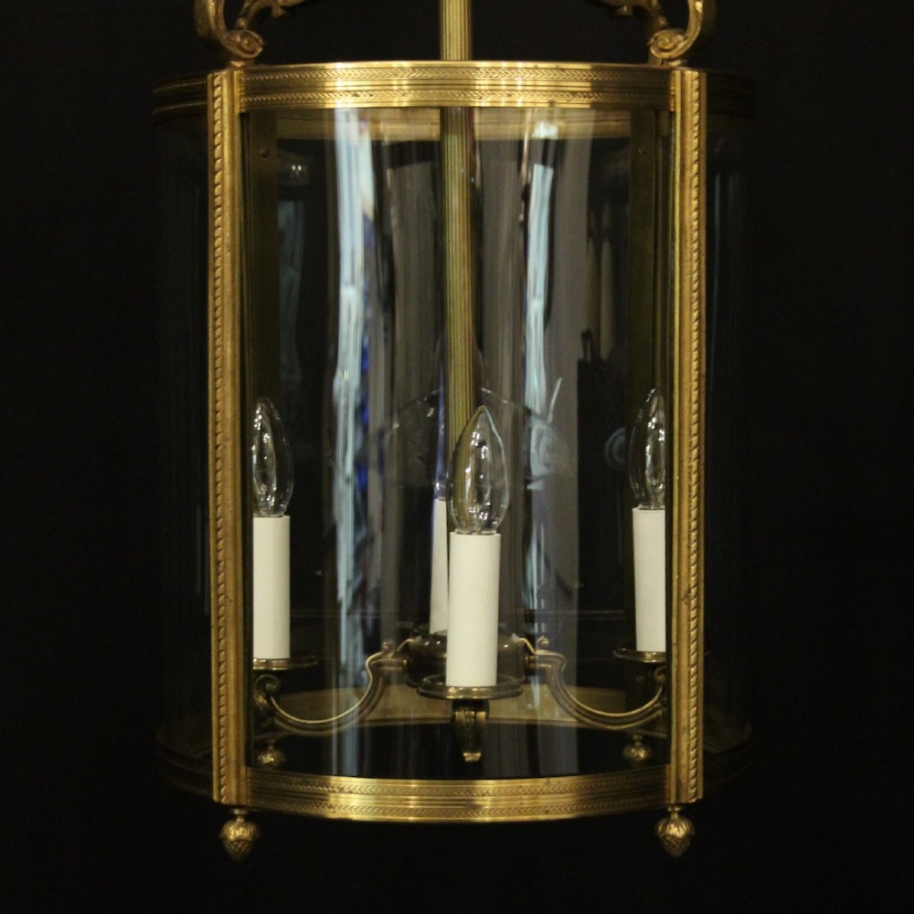 A French gilt bronze cylindrical hall lantern with curved glass panels and internal candle sockets. View IV
