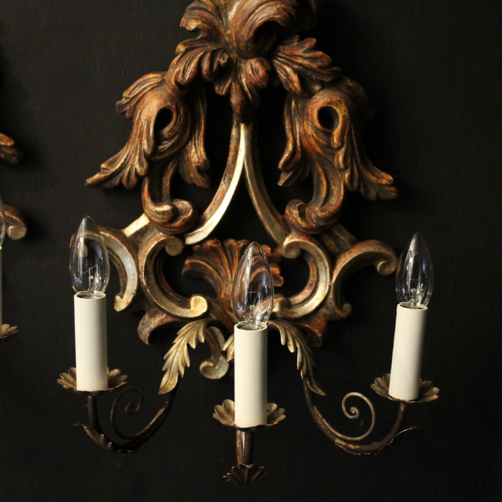A pair of carved giltwood three-arm Florentine wall lights with ornate acanthus leaf scrollwork and candle sleeves. View III