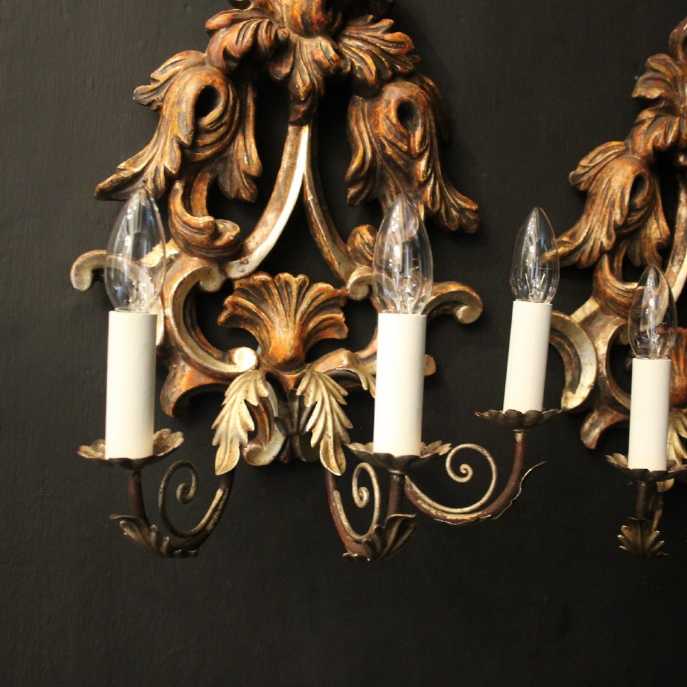 A pair of carved giltwood three-arm Florentine wall lights with ornate acanthus leaf scrollwork and candle sleeves. View VI