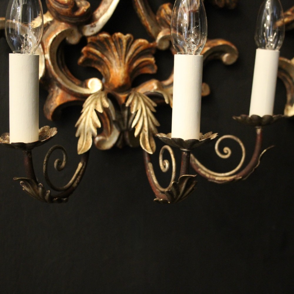 A pair of carved giltwood three-arm Florentine wall lights with ornate acanthus leaf scrollwork and candle sleeves. View VII
