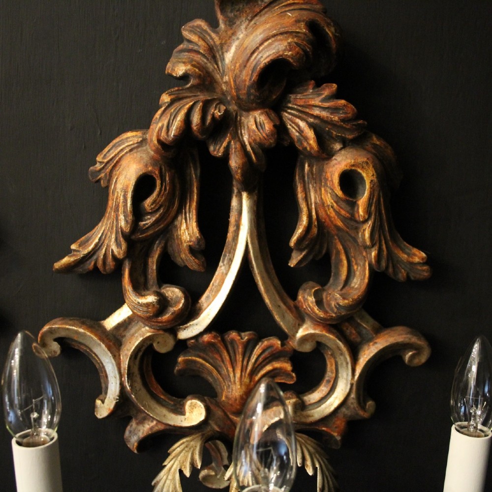 A pair of carved giltwood three-arm Florentine wall lights with ornate acanthus leaf scrollwork and candle sleeves. View VIII