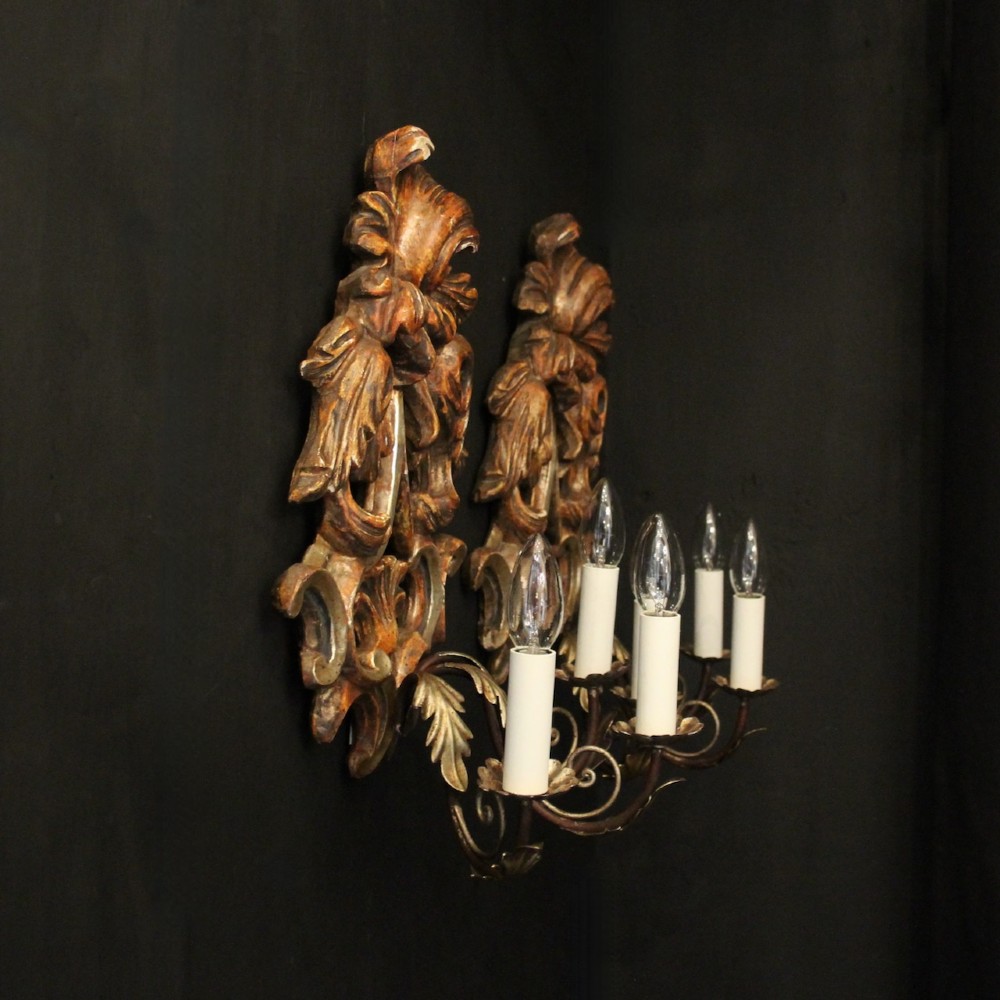 A pair of carved giltwood three-arm Florentine wall lights with ornate acanthus leaf scrollwork and candle sleeves. View X