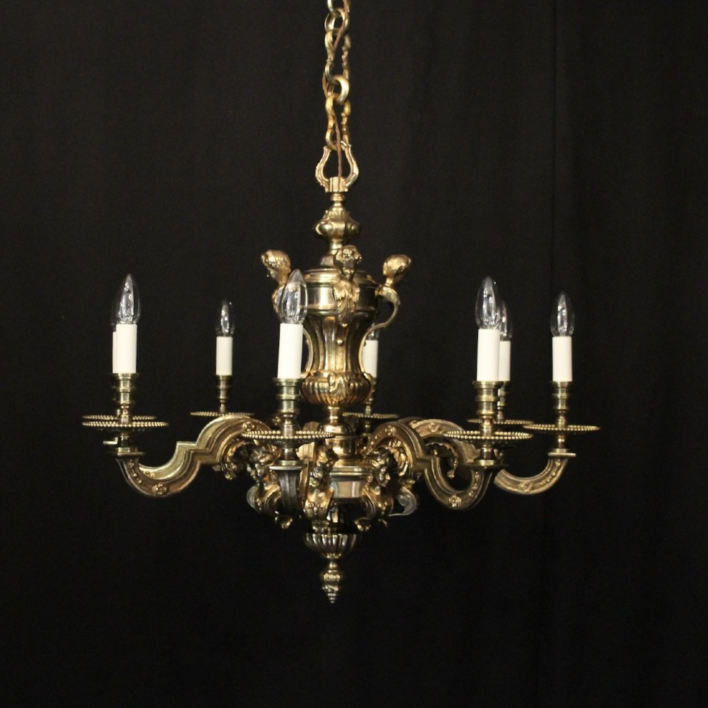 An eight-arm French gilded bronze chandelier with central scrolling stem and candle-effect bulb holders suspended from a chain.