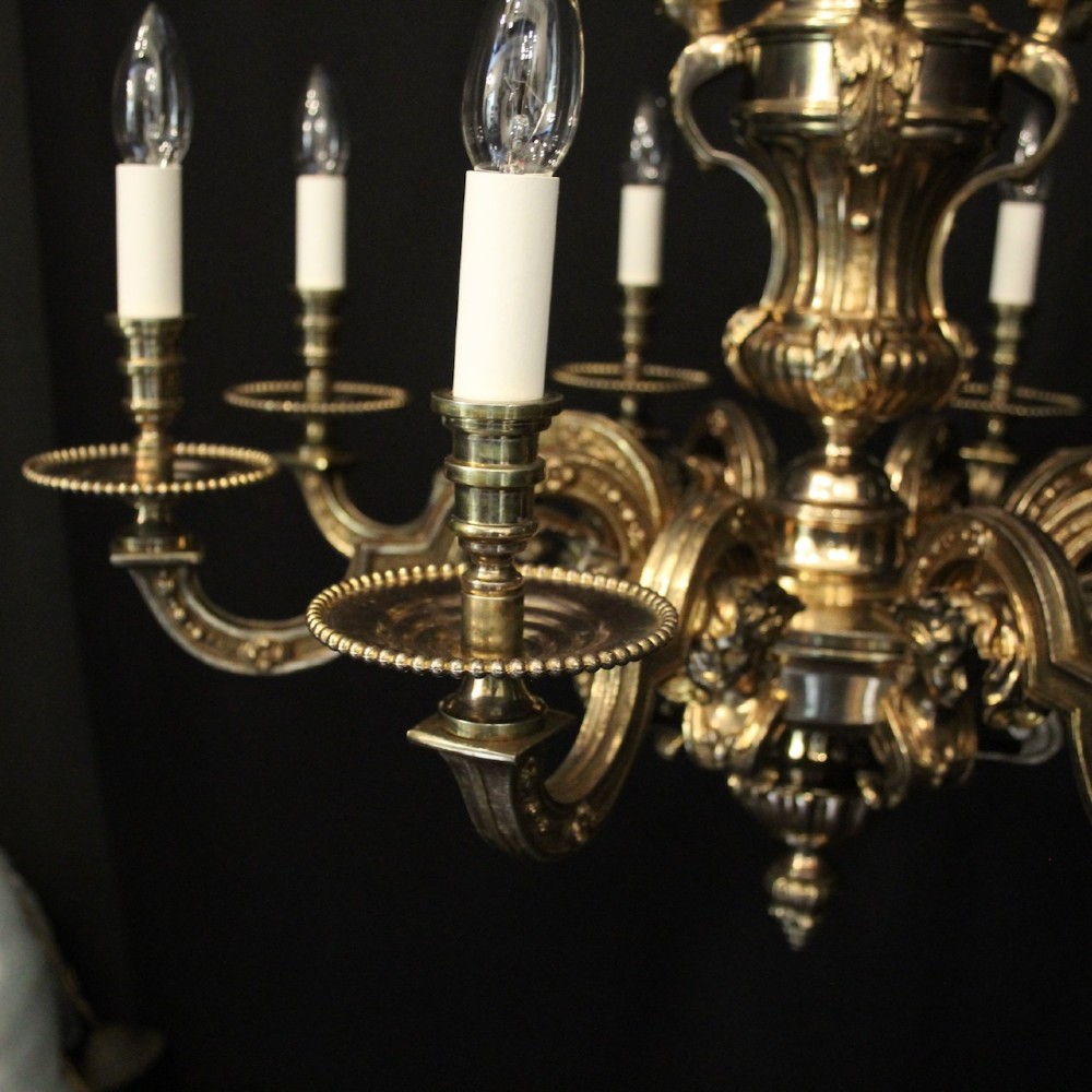 An eight-arm French gilded bronze chandelier with central scrolling stem and candle-effect bulb holders suspended from a chain. View IV