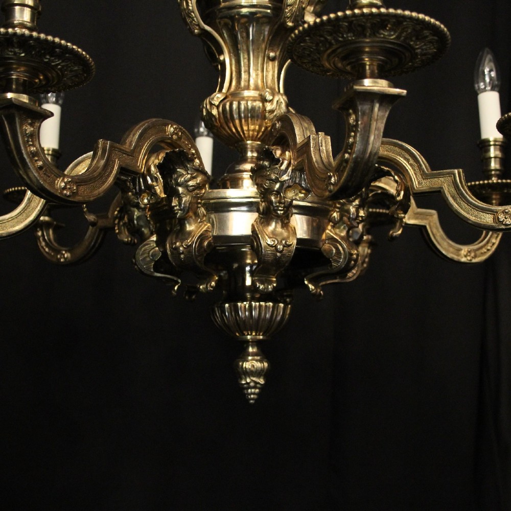 An eight-arm French gilded bronze chandelier with central scrolling stem and candle-effect bulb holders suspended from a chain. View IX