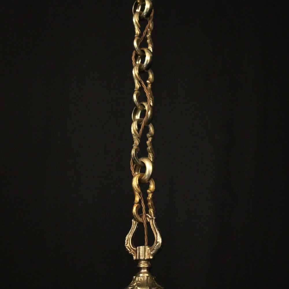 An eight-arm French gilded bronze chandelier with central scrolling stem and candle-effect bulb holders suspended from a chain. View X