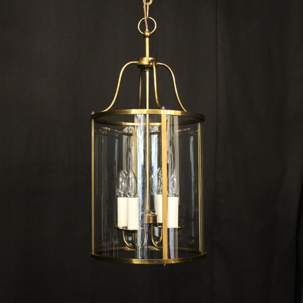 A cylindrical gilded brass hall lantern featuring curved convex glass panels and an internal four-light cluster.