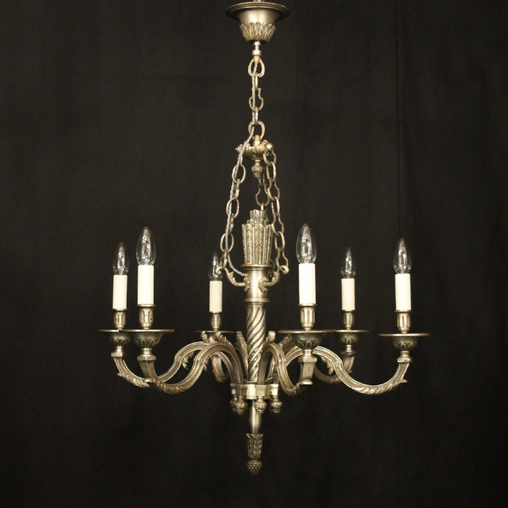 A six-arm French silver-gilded bronze chandelier featuring decorative fluted central columns, carved foliage motifs, and faux candle sleeves against a dark background. View II