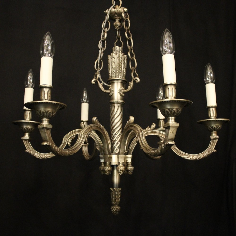 A six-arm French silver-gilded bronze chandelier featuring decorative fluted central columns, carved foliage motifs, and faux candle sleeves against a dark background. View III