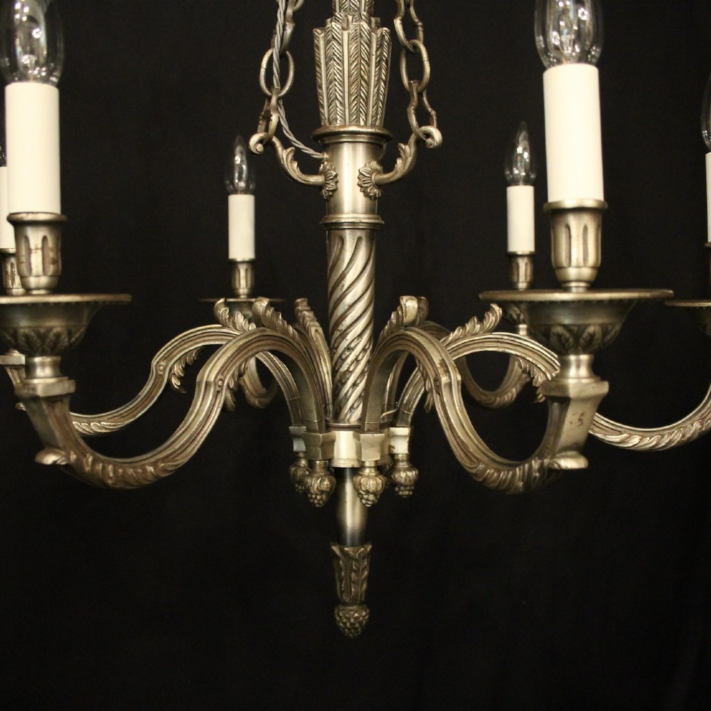 A six-arm French silver-gilded bronze chandelier featuring decorative fluted central columns, carved foliage motifs, and faux candle sleeves against a dark background. View IV