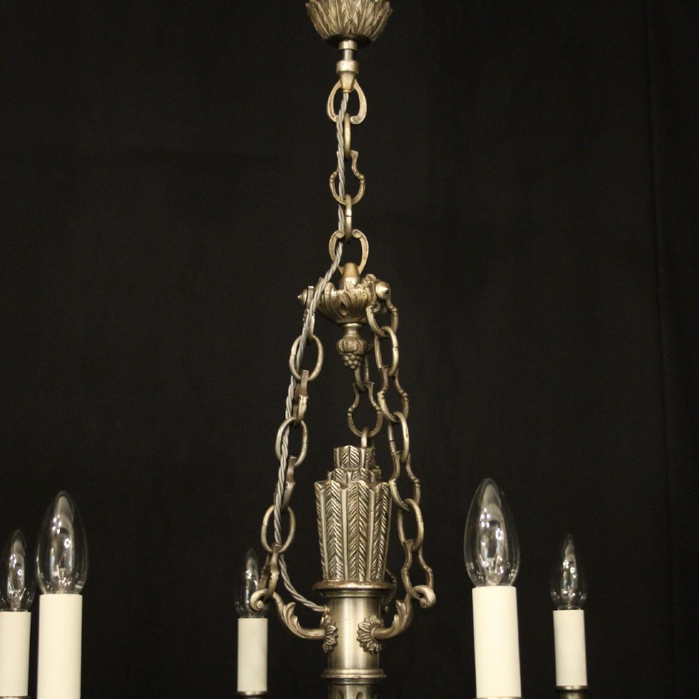A six-arm French silver-gilded bronze chandelier featuring decorative fluted central columns, carved foliage motifs, and faux candle sleeves against a dark background. View VII