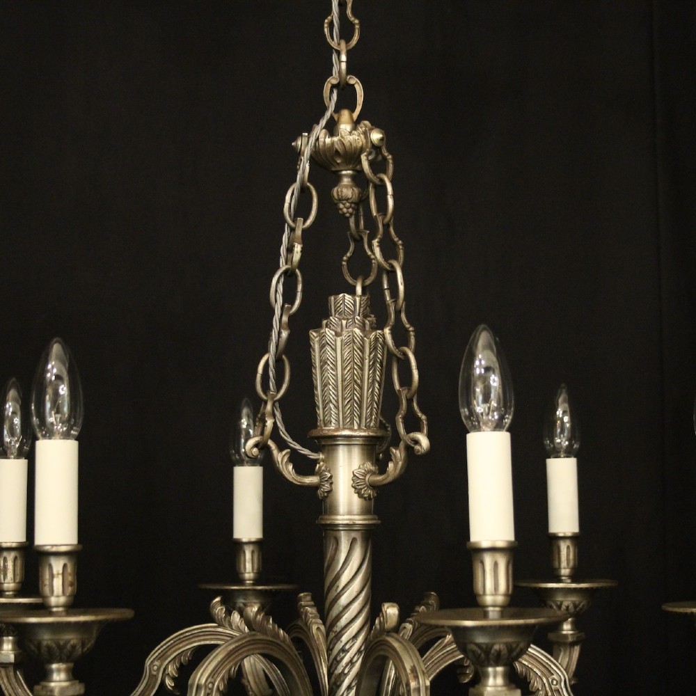 A six-arm French silver-gilded bronze chandelier featuring decorative fluted central columns, carved foliage motifs, and faux candle sleeves against a dark background. View VIII