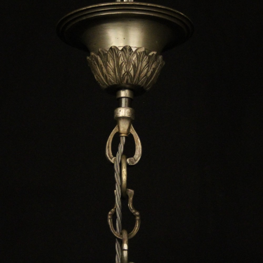 A six-arm French silver-gilded bronze chandelier featuring decorative fluted central columns, carved foliage motifs, and faux candle sleeves against a dark background. View X