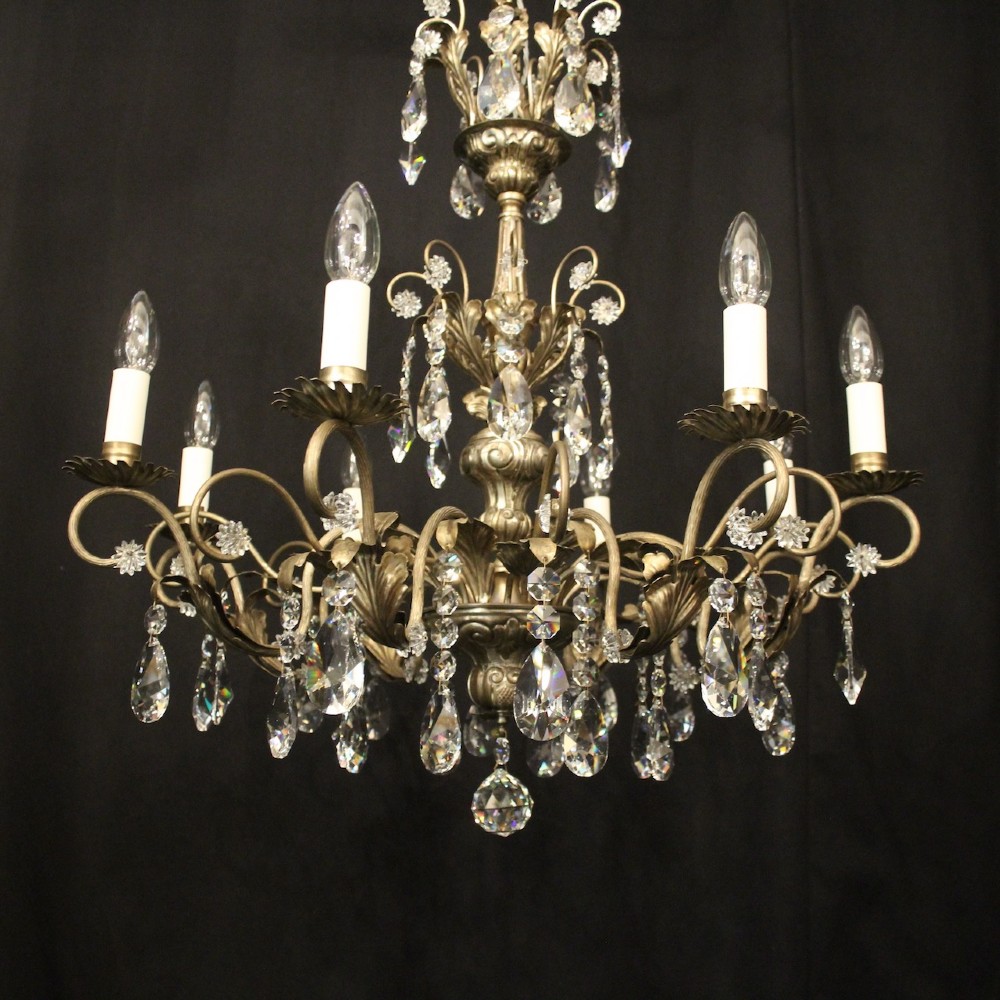 An eight-light Italian chandelier featuring a silvered metal frame decorated with scrolling arms, hanging crystal drops, and glass rosettes. View II