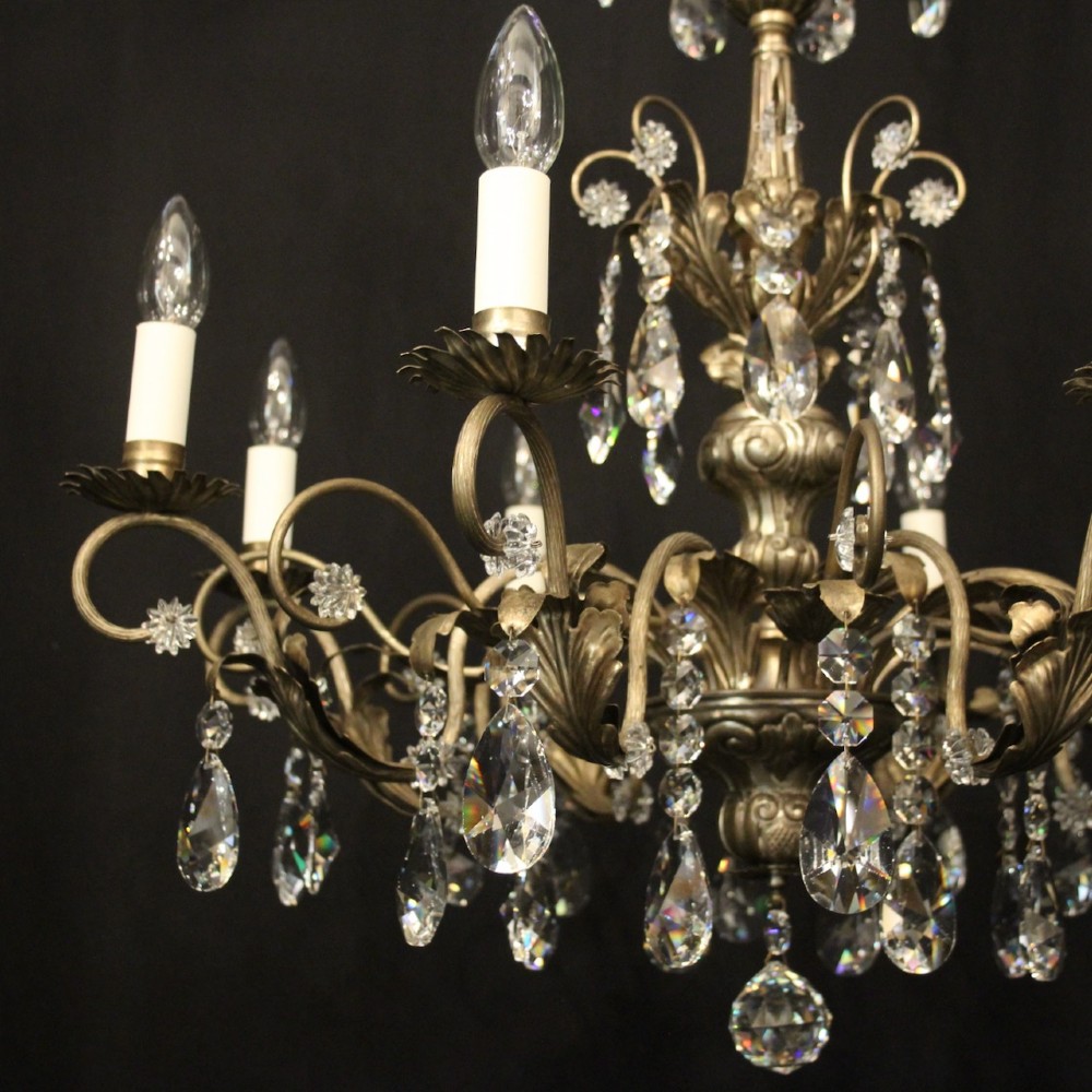 An eight-light Italian chandelier featuring a silvered metal frame decorated with scrolling arms, hanging crystal drops, and glass rosettes. View III