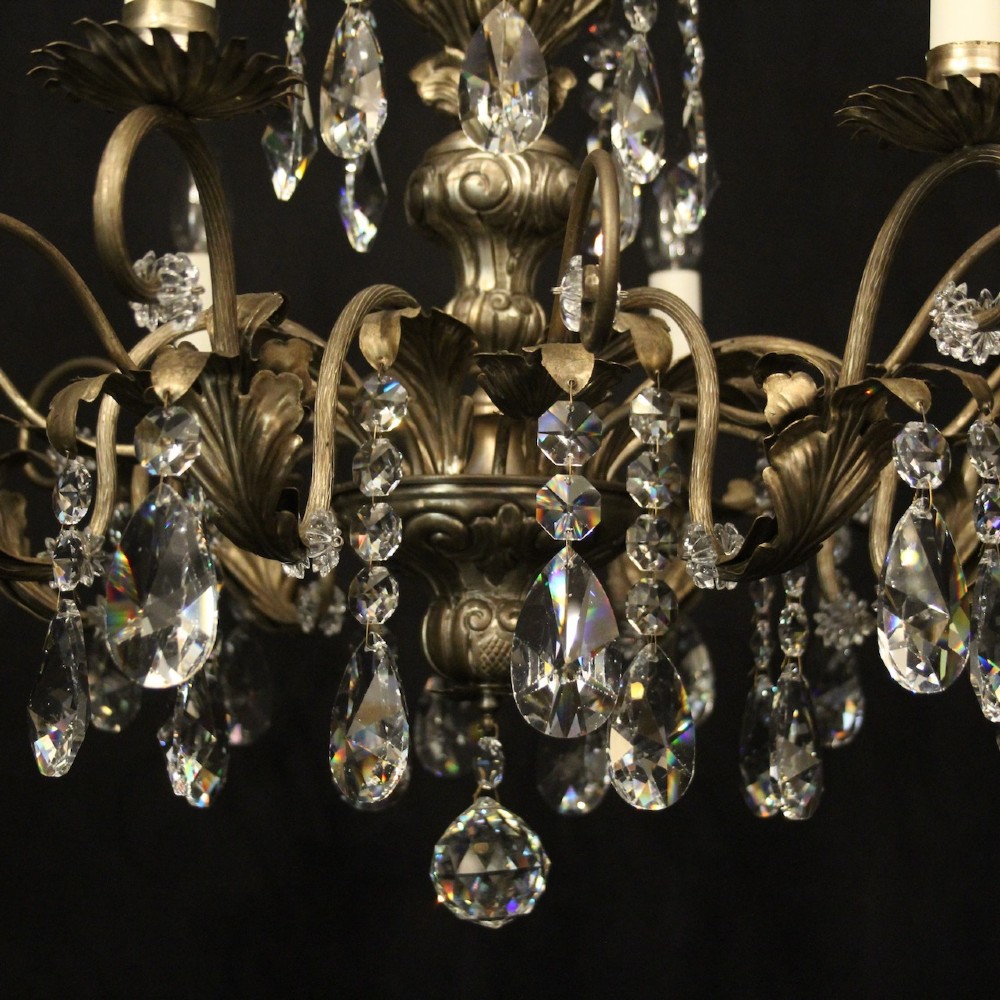 An eight-light Italian chandelier featuring a silvered metal frame decorated with scrolling arms, hanging crystal drops, and glass rosettes. View V