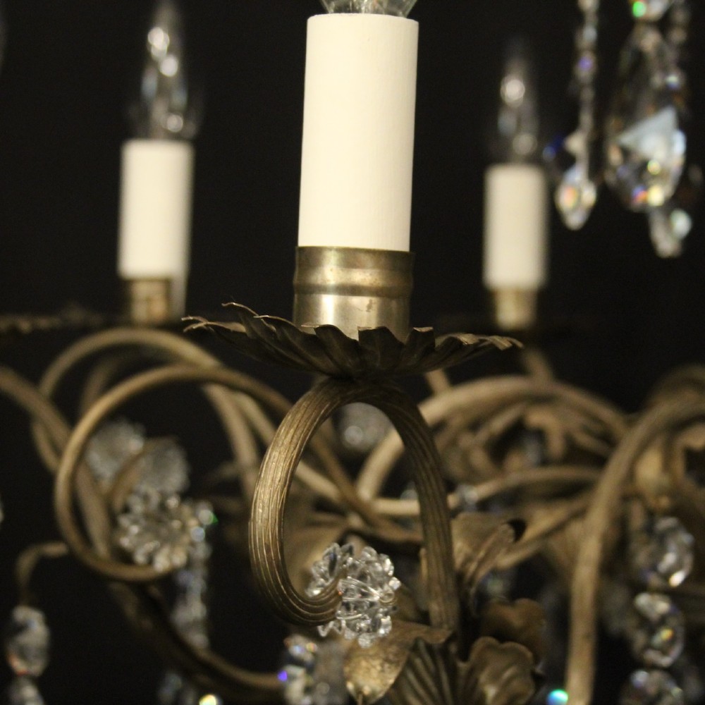 An eight-light Italian chandelier featuring a silvered metal frame decorated with scrolling arms, hanging crystal drops, and glass rosettes. View VII