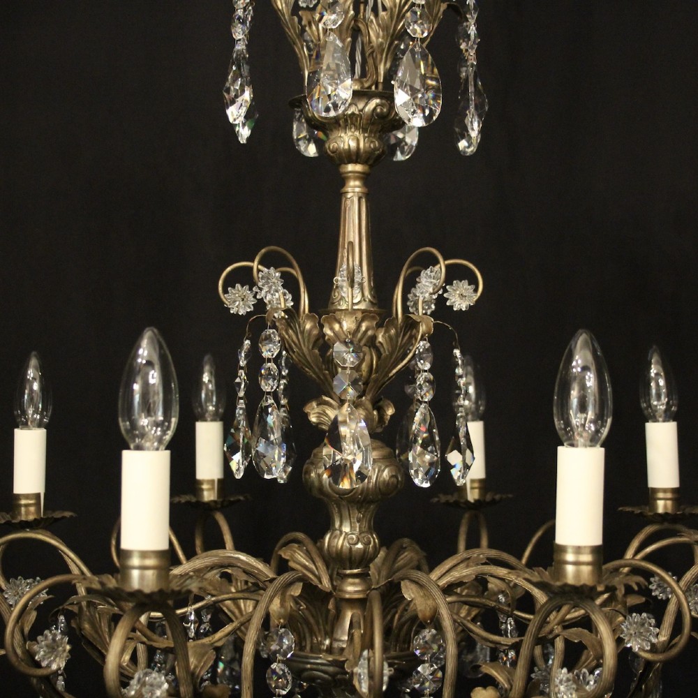 An eight-light Italian chandelier featuring a silvered metal frame decorated with scrolling arms, hanging crystal drops, and glass rosettes. View IX