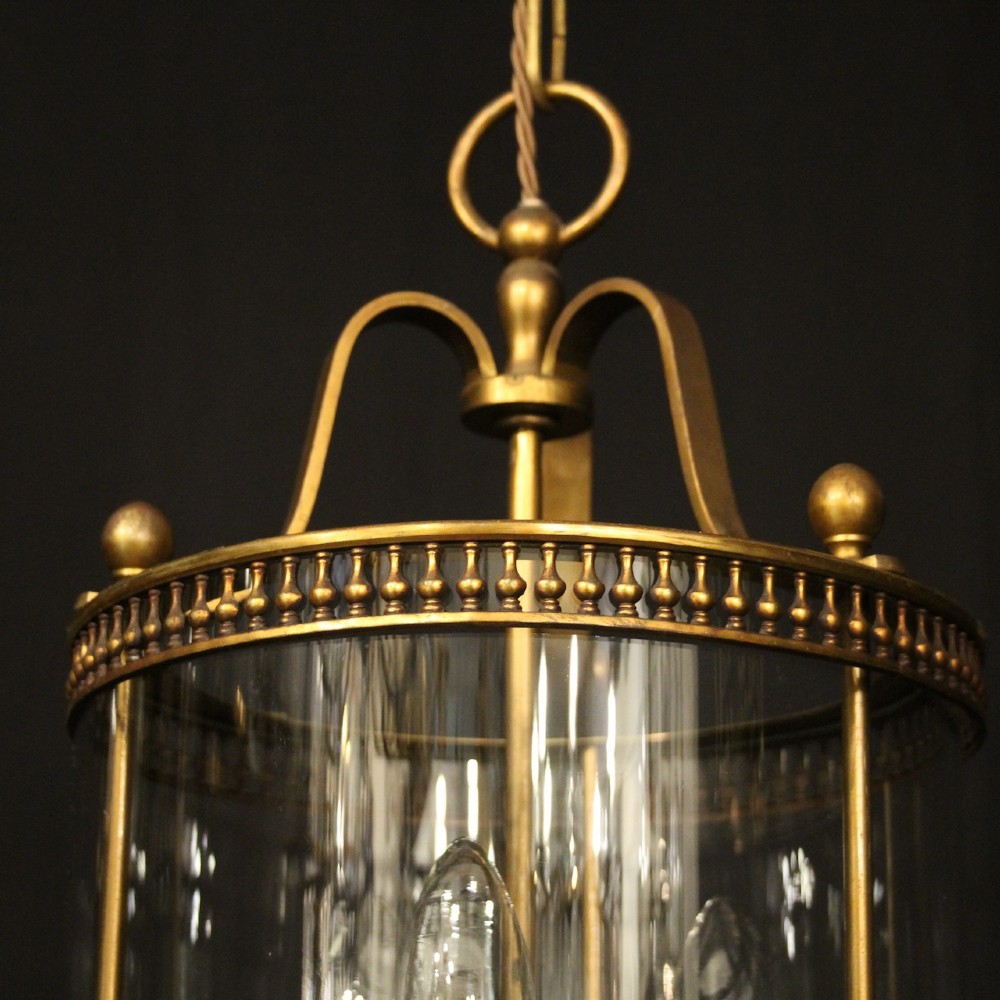 A cylindrical antique French hall lantern crafted from gilded brass with clear glass panels housing a three-light candle cluster. View IV