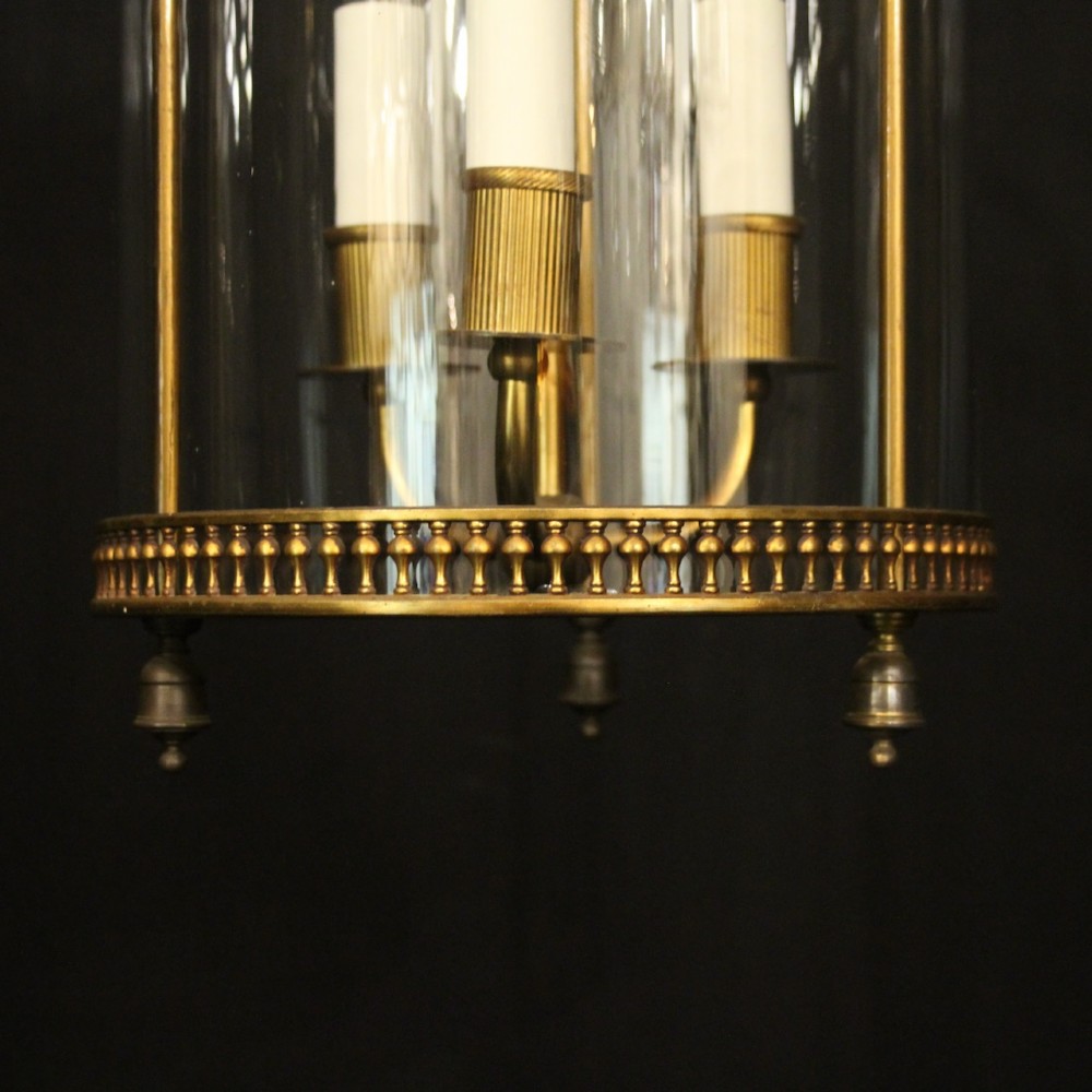 A cylindrical antique French hall lantern crafted from gilded brass with clear glass panels housing a three-light candle cluster. View VI
