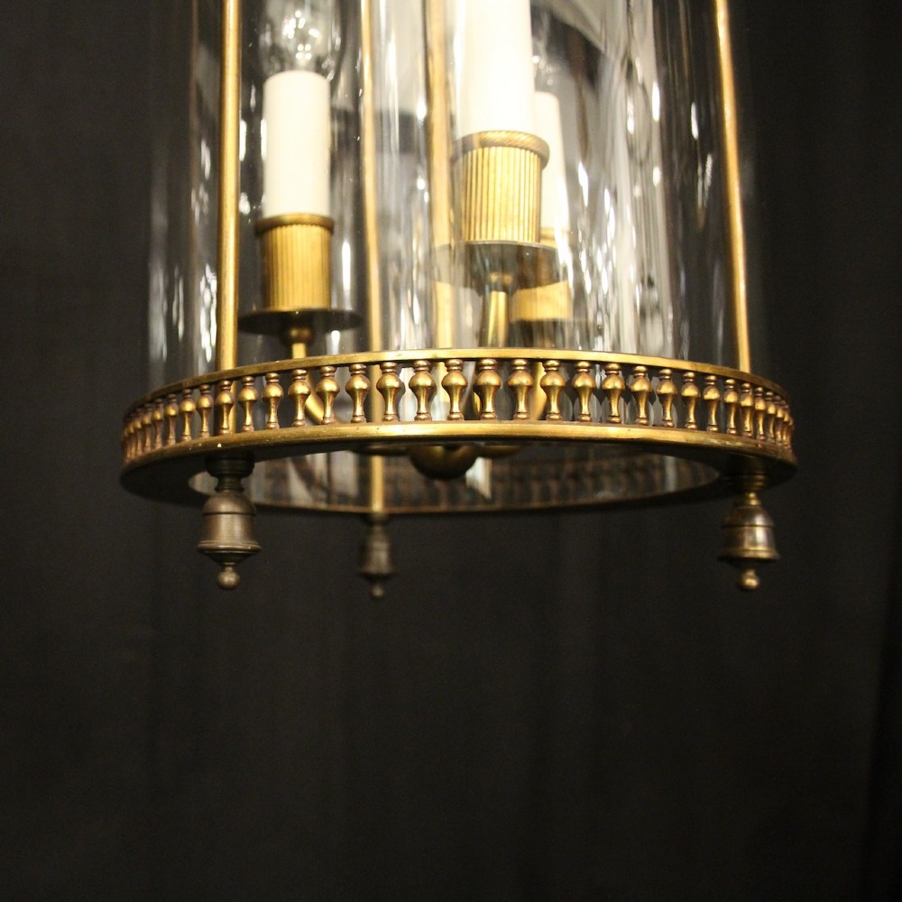 A cylindrical antique French hall lantern crafted from gilded brass with clear glass panels housing a three-light candle cluster. View VIII
