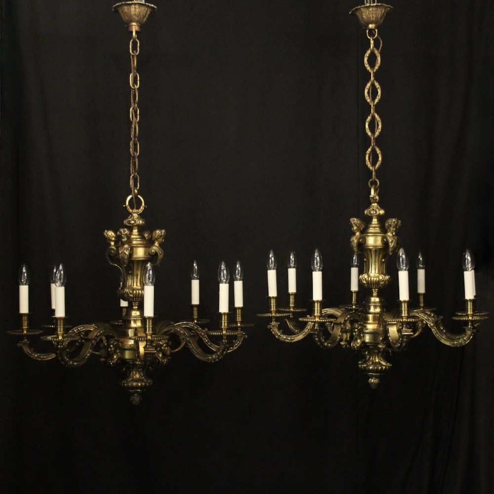 A matching pair of cast bronze eight-light chandeliers featuring ornate scrolled arms, decorative stem castings, and faux candle sleeves. View II