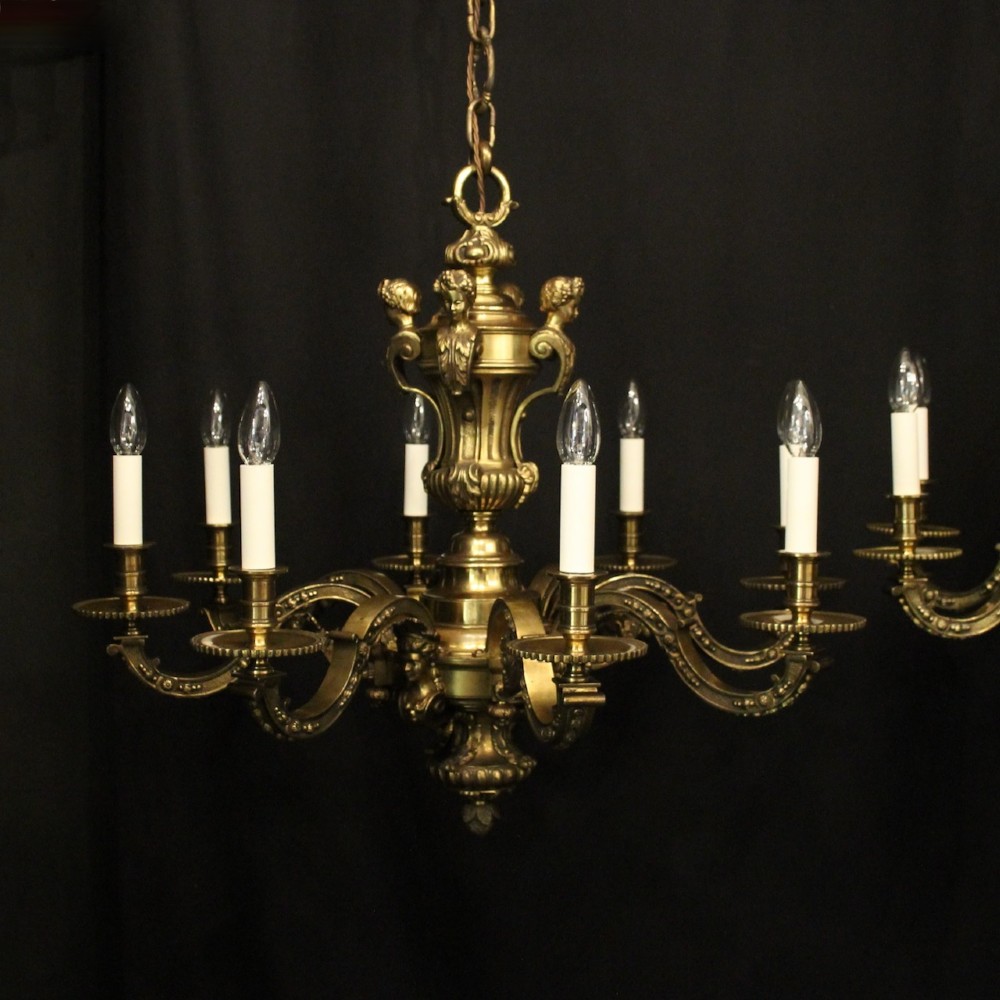 A matching pair of cast bronze eight-light chandeliers featuring ornate scrolled arms, decorative stem castings, and faux candle sleeves. View III
