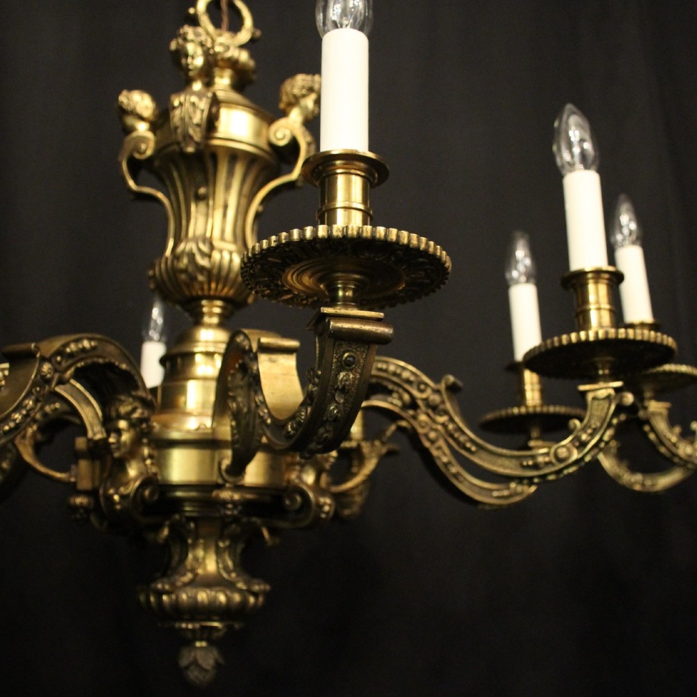 A matching pair of cast bronze eight-light chandeliers featuring ornate scrolled arms, decorative stem castings, and faux candle sleeves. View IV