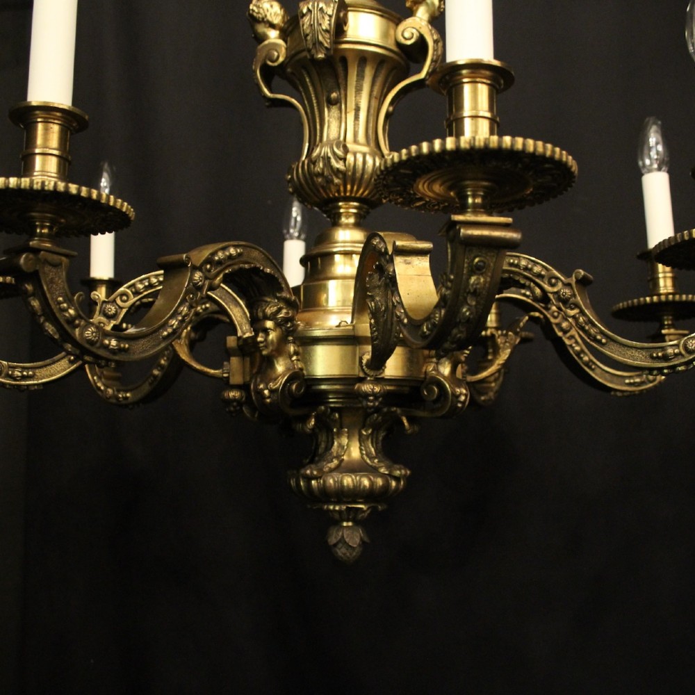 A matching pair of cast bronze eight-light chandeliers featuring ornate scrolled arms, decorative stem castings, and faux candle sleeves. View V