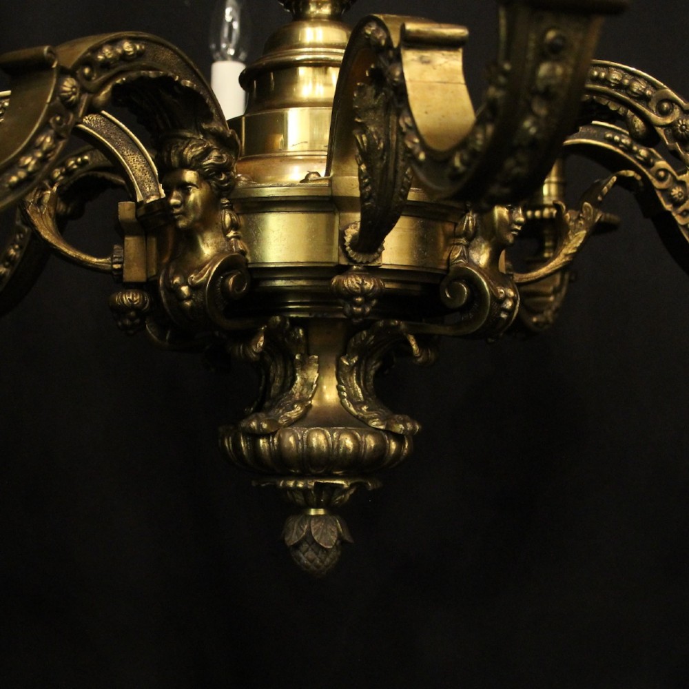 A matching pair of cast bronze eight-light chandeliers featuring ornate scrolled arms, decorative stem castings, and faux candle sleeves. View VI