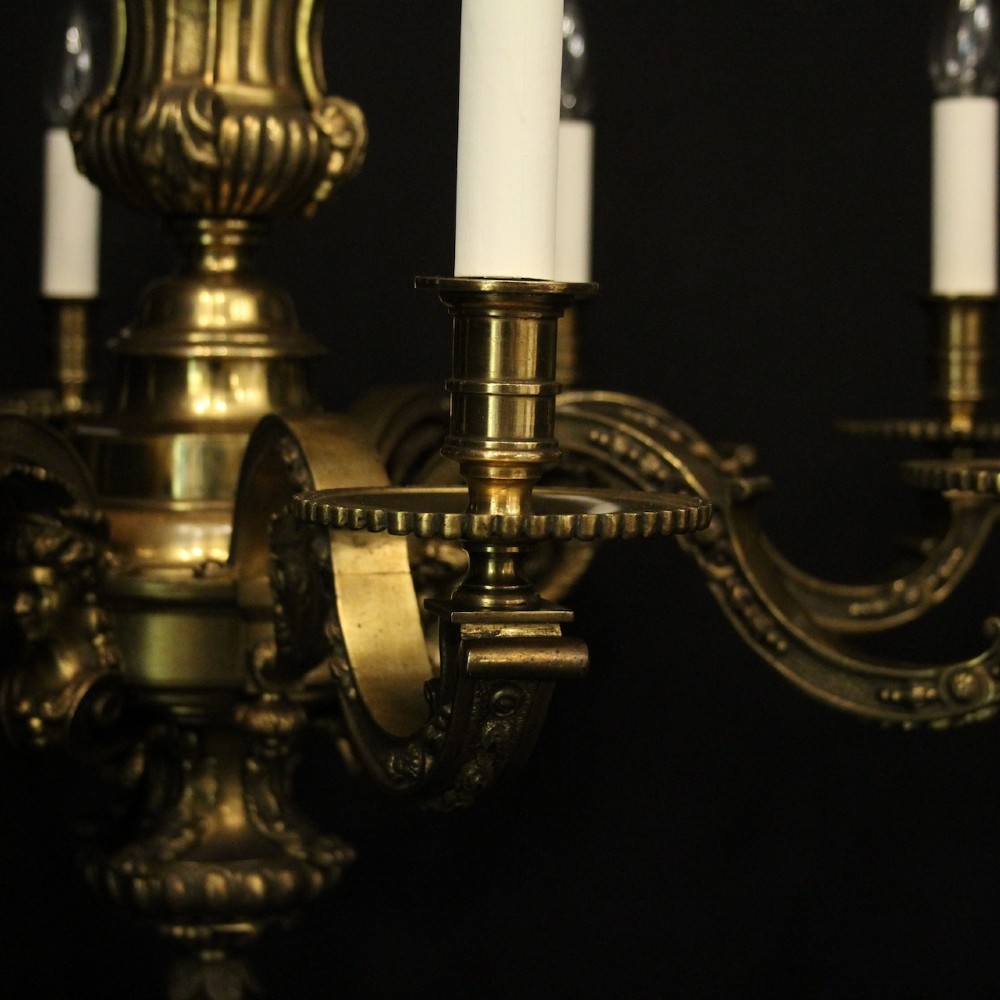A matching pair of cast bronze eight-light chandeliers featuring ornate scrolled arms, decorative stem castings, and faux candle sleeves. View VII