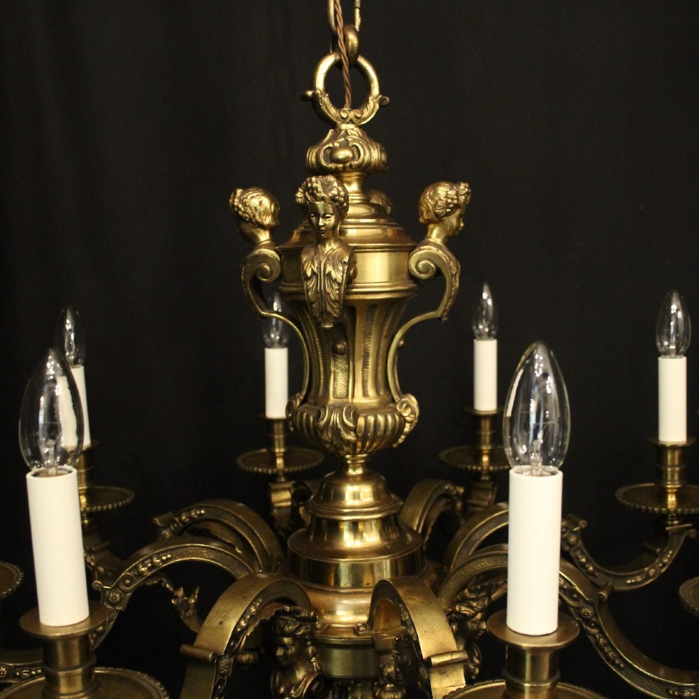 A matching pair of cast bronze eight-light chandeliers featuring ornate scrolled arms, decorative stem castings, and faux candle sleeves. View VIII