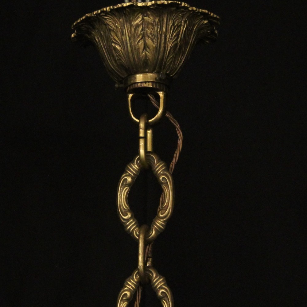 A matching pair of cast bronze eight-light chandeliers featuring ornate scrolled arms, decorative stem castings, and faux candle sleeves. View X