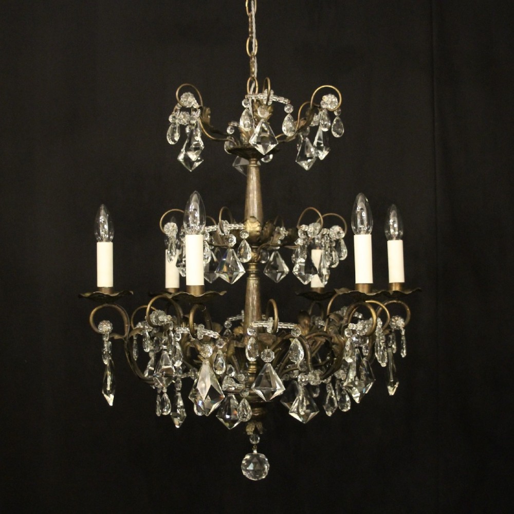 An Italian multi-tiered chandelier featuring a patinated silvered frame adorned with hanging cut-crystal drops, faceted pendants, and six candle-effect light fittings.
