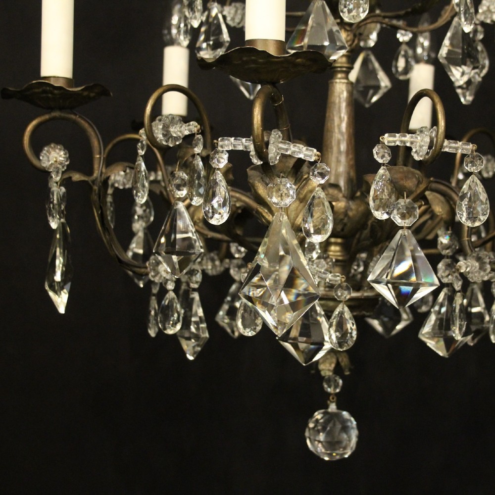 An Italian multi-tiered chandelier featuring a patinated silvered frame adorned with hanging cut-crystal drops, faceted pendants, and six candle-effect light fittings. View III