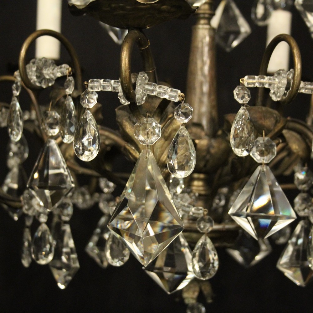 An Italian multi-tiered chandelier featuring a patinated silvered frame adorned with hanging cut-crystal drops, faceted pendants, and six candle-effect light fittings. View IV