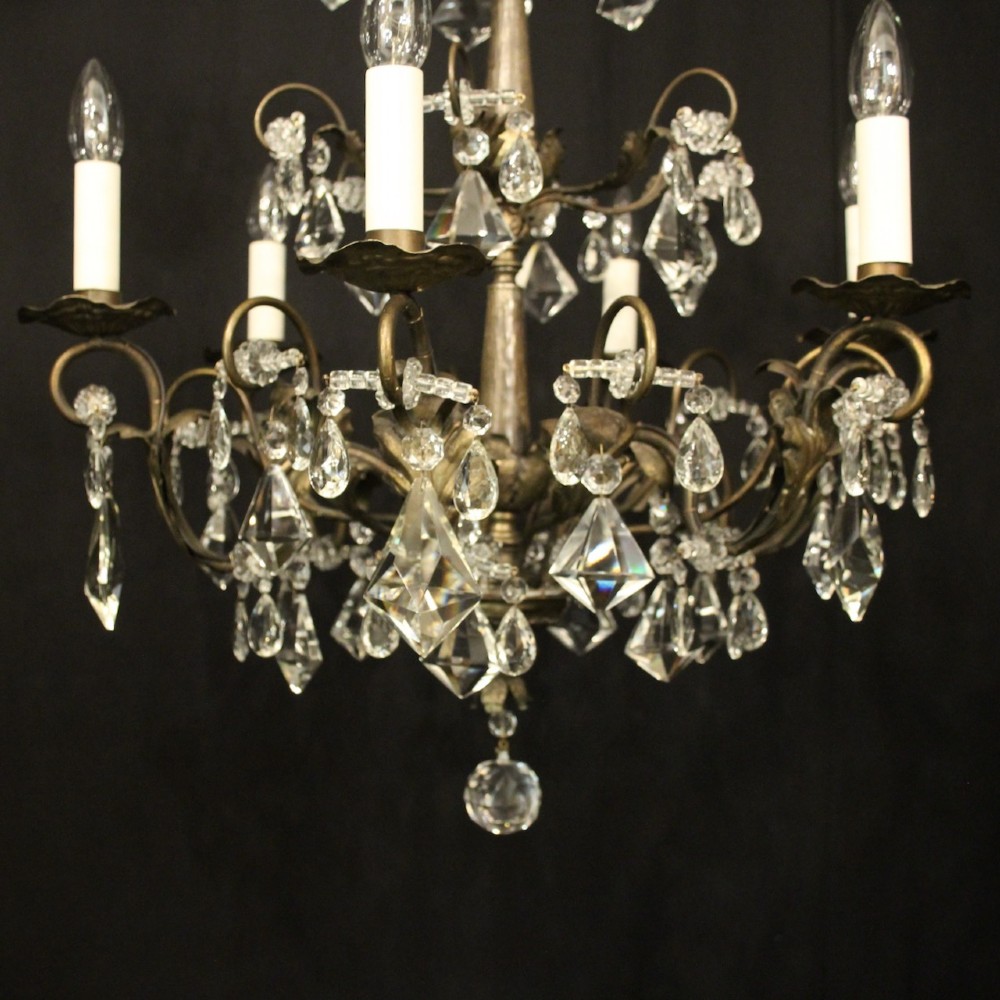 An Italian multi-tiered chandelier featuring a patinated silvered frame adorned with hanging cut-crystal drops, faceted pendants, and six candle-effect light fittings. View V
