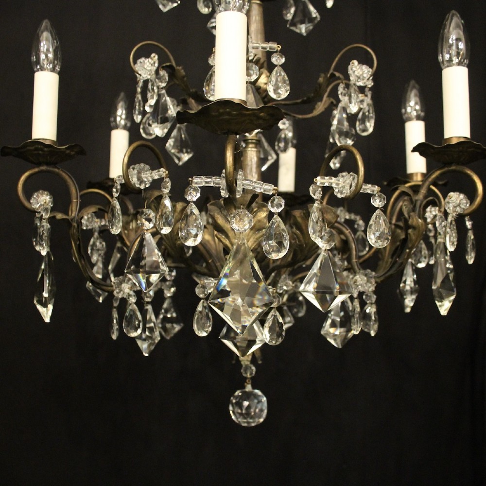 An Italian multi-tiered chandelier featuring a patinated silvered frame adorned with hanging cut-crystal drops, faceted pendants, and six candle-effect light fittings. View VI