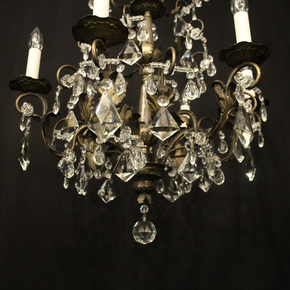 An Italian multi-tiered chandelier featuring a patinated silvered frame adorned with hanging cut-crystal drops, faceted pendants, and six candle-effect light fittings. View VII