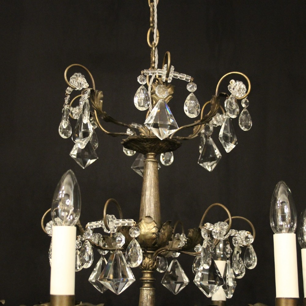 An Italian multi-tiered chandelier featuring a patinated silvered frame adorned with hanging cut-crystal drops, faceted pendants, and six candle-effect light fittings. View VIII
