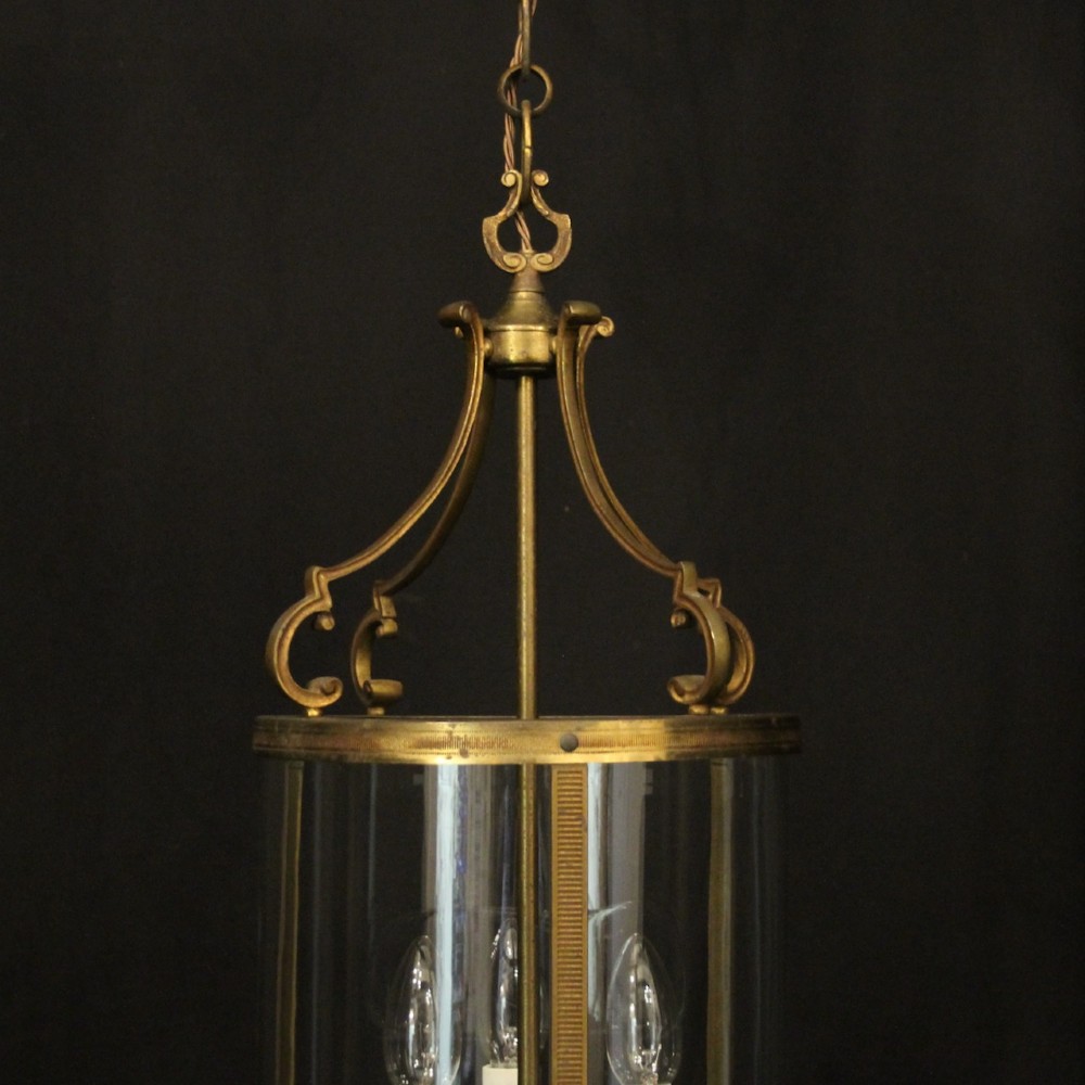 An antique French cylindrical hall lantern featuring a gilded brass frame, curved glass panels, and a three-light interior fitting suspended from a hook. View IV