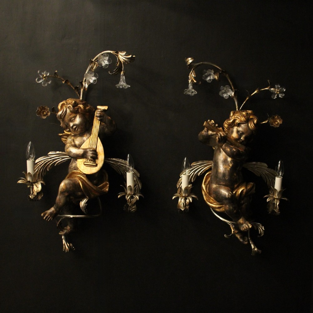 Pair of Italian giltwood wall sconces featuring sculpted cherubs playing musical instruments framed by metal branches with clear glass flowers.