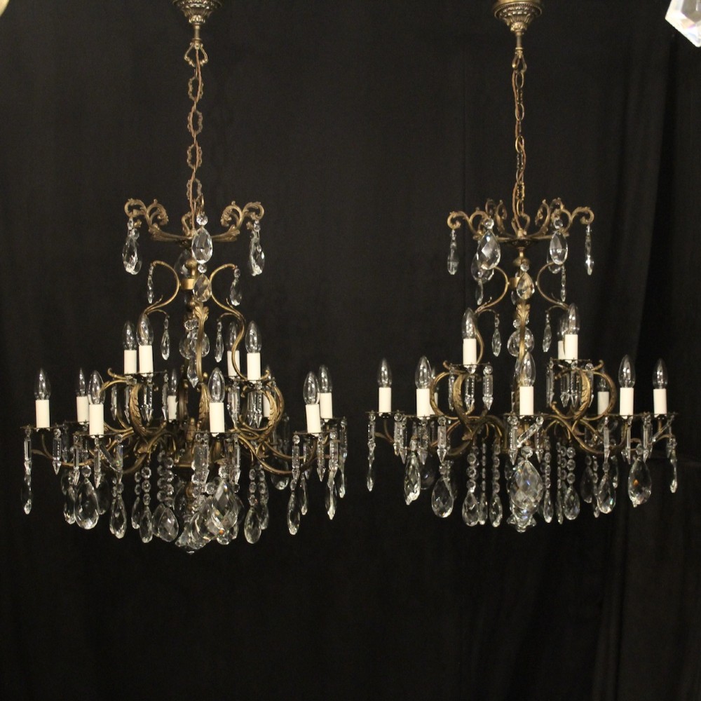 A pair of tiered French brass chandeliers featuring twelve lights each and clear glass crystal drops.
