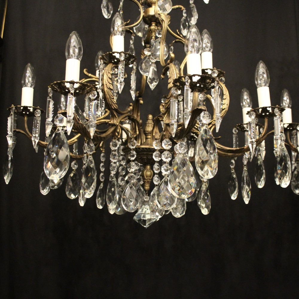 A pair of tiered French brass chandeliers featuring twelve lights each and clear glass crystal drops. View III
