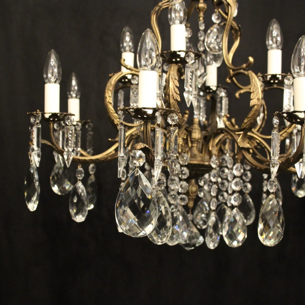 A pair of tiered French brass chandeliers featuring twelve lights each and clear glass crystal drops. View IV